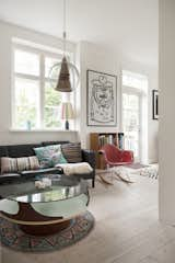 More color is found in the living area's tapestries, including a round rug and  multiple sofa pillows. A contemporary brass and glass pendant light hangs above the glass coffee table.