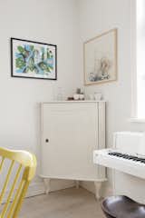 Corner vignette of dining room with white antique cabinet and modern art