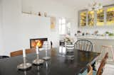 Open dining room and kitchen featuring yellow stained glass cabinets, large black wooden table, and fireplace.