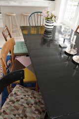 Black wooden dining table with mismatched wooden chairs and colorful chair cushions.