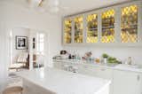 Kitchen, Marble Counter, Dishwasher, Range, Colorful Cabinet, Ceiling Lighting, and Drop In Sink Sleek white kitchen is given a pop of color and old world charm with yellow stained glass cabinets. Luxurious marble countertop and island are also featured.  Photos from Colorful & Eclectic Danish Home