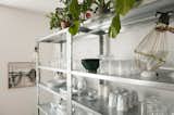 Open metal shelving filled with glassware and ceramic cups and dishes