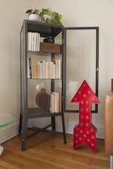 A handmade red arrow  lamps sits near a glass bookcase