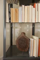 Books with their spines turned away sit in the metal and glass bookcase