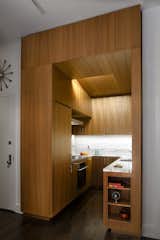 We designed this kitchen like a single piece of teak cabinetry. Lighting and ventilation are recessed into the angled ceiling plane; deep storage is located over the entrance.