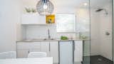 Glass partition instead of a traditional wall allows for keeping the space visually open. The kitchen countertop cuts glass and continues into a bathroom area becoming a vanity top. 
