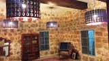 Living Room featuring limestone walls, metal Lebanese style windows, modern display cabinet, Mahogany cladded roof drop beams, dark blue large style cushions, and copper two feet diameter 18th Century tray showing to the right being made ready to hang on the stone walls...