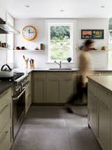Large porcelain tile floor, pale green cabinets, wood-topped island