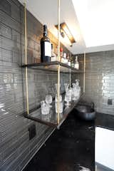 the custom built metal shelves with glass inlay are suspended from the ceiling and finish off the fabulous custom bar area. the back splash has been laid in a brick pattern and is glass tile. together with the black soapstone, solid lava stone bar sink and beautiful retro faucet the look is complete!