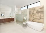 Bath Room, Porcelain Tile Floor, Wall Lighting, Quartzite Counter, Ceiling Lighting, Stone Tile Wall, One Piece Toilet, Freestanding Tub, Drop In Sink, and Enclosed Shower A Japanese screen, a family heirloom from the wife's grandmother, creates a sense of zen  in the primary bathroom.  Photo 12 of 17 in North Dallas by Mary Anne Smiley