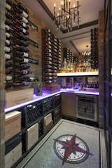 This climate controlled wine room is surrounded by glass and steel and showcases a custom mosaic floor sporting the client's former business logo. Th thick textured glass is backlit and can be changed to any color. 