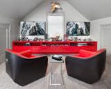 In a little nook in the space, a wall to wall console holds all their gaming systems, including controllers. There is no fighting for screen time because each boy has their own screen. The red and black Walter Knoll swivel chairs allows them to play together or on their own.