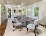 Keeping with the style of the house, the walls have a venetian plaster finish in a soft cream tone. Both the buffet and cabinet, original to the space, got updated with a matching lacquer paint finish to tie into the walls. Continuing the desire to bring the space into the 21st century, the dining table is a thick piece of lavender crackle resin that sits atop smokey acrylic pedestal bases. Classic Klismos chairs from Nancy Corzine, covered in Sabina Fey velvet, surround the table.