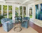 The sunroom, right off the sitting room, is home to a simple game table and swive chairs with views to the backyard.