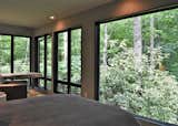 Bedroom, Recessed Lighting, Bed, Light Hardwood Floor, Ceiling Lighting, and Floor Lighting The primary suite seems to float over hundreds of mature rhododendron maximums.   Photo 5 of 14 in Appalachian Black Dogtrot by Jay Sifford