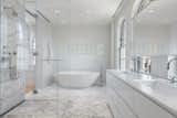 A master bath clad in marble with stand-alone tub. 