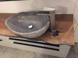 A stone bathroom sink, mixed with a stainless steel faucet & a tree slice counter top. Amazing!
