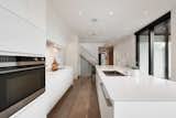 Kitchen, Refrigerator, Wall Oven, Cooktops, White Cabinet, Concrete Floor, Ceiling Lighting, Undermount Sink, and Marble Counter  Photo 7 of 18 in Oak Residence by Hatem+D / Etienne Bernier Architecte