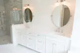 Master bath with double sink vanity, marble floor and corner shower.