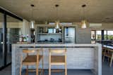 Kitchen, Refrigerator, Concrete Counter, Concrete Floor, Open Cabinet, Concrete Backsplashe, Ceiling Lighting, Pendant Lighting, Drop In Sink, and Microwave  Photo 16 of 33 in La Marina House by Besonías Almeida arquitectos