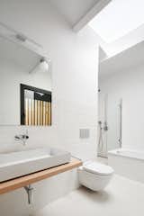 Bath Room, Vessel Sink, Wall Lighting, Wood Counter, Alcove Tub, Ceiling Lighting, Concrete Floor, Subway Tile Wall, One Piece Toilet, and Open Shower Suite bathroom with skylight  Photo 4 of 30 in Bathroom by Yuki Kaneko from Conversion of a ground-floor publisher’s warehouse into a residence and atelier for an artist-architect couple
