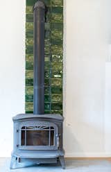 There is a cast-iron stove between a dining room and a living room with kitchen.
