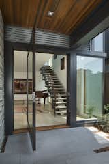 Large glass pivot door at front entry and stair inside. 