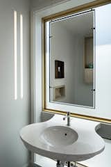 Powder room with sculptural quartz vanity and suspended steel mirror frame.