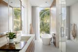 Bath Room, Stone Slab Wall, Concrete Counter, Porcelain Tile Floor, Freestanding Tub, Ceiling Lighting, Recessed Lighting, Soaking Tub, Wall Mount Sink, One Piece Toilet, and Enclosed Shower  Photo 7 of 28 in Bayview House by Leader Design Studio