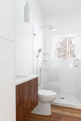 Bath Room, Engineered Quartz Counter, Medium Hardwood Floor, Drop In Sink, Enclosed Shower, One Piece Toilet, and Pendant Lighting Guest bath features wood details  Photo 9 of 16 in The Glass House by AmyDutton Home
