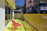 Outdoor, Large Patio, Porch, Deck, Wire Fences, Wall, and Metal Patio, Porch, Deck 24d-studio 2nd floor bright yellow east balcony with plants and pink and blue chairs in the background  Photo 19 of 22 in House Of Many Arches by Marina Topunova