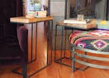 A pair of nesting side tables made from reclaimed wood and steel provide table space for the main floor living room. The purple velvet chair is by Arhaus, and the gray silk pillow is  Anatolian. The couple used an old Turkish Kilim to upholster the ottoman. 