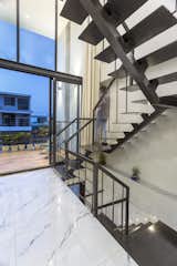The largesse of this space has been further realized with a play of proportions, by providing full height glass screen which showcases the sculptural sparkling grey metal staircase; gracing the double height volume.
The glass screen allows the stairwell to engulf bundles of natural light, which then bathe the interior spaces, such as the main living area, in a balanced light through the cut-outs. 
