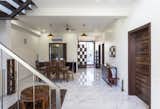 A visual continuity of spaces is achieved along the central spine with the rear wall of the house visible from the entrance itself, thus, uniting a sequence of spaces, i.e., the Front garden, Entrance foyer, Hallway, Puja room and the Rear deck through this visual linkage. The well-lit entrance foyer with double – height space uniformly spreads the daylight in every part, adorning it with a welcoming appeal. Functionally, the Puja space has been given a centric placement, and its double–height allows for a continuous cycle of energy flowing throughout the house.

Captivation towards the time–honored design styles, client being a native of Rajasthan, directed the strategy for a subtle but elegant lot of material, color and texture selection for the interiors. Ochre toned wood finishes used for the furnishings and Coreal satin walnut veneer finish (imported from USA) for the doors become the cynosure against the neutral backdrop set by white walls and floor. 

The assorted selection of furnishings applause the authenticity of the interior spaces and complements the material palette even in the absence of false ceiling. 
