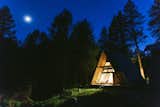 A view of the A-frame cabin glowing at night.