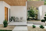 Thermotreated wood cladding in the ceiling of this front porch compliments the stucco walls surrounding it. Solid white oak front door with a sidelight creates inviting entry to the home while keeping it semi private.
