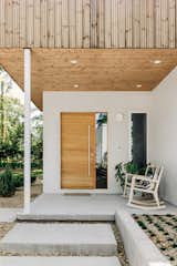 Thermotreated wood cladding in the ceiling of this front porch compliments the stucco walls surrounding it. Solid white oak front door with a sidelight creates inviting entry to the home while keeping it semi private.