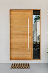 Thermotreated wood cladding in the ceiling of this front porch compliments the stucco walls surrounding it. Solid white oak front door with a sidelight creates inviting entry to the home while keeping it semi private.