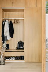 Built in white oak coat closet and a bench with more storage behing a sliding door is a practical but beautiful solution for the main entry