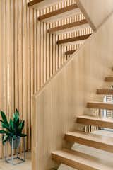 This floating white oak staircase was custom designed for this project, where the wooden slat wall serves as a railing and a partition wall between the staircase and the dining room