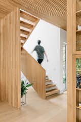 This floating white oak staircase was custom designed for this project, where the wooden slat wall serves as a railing and a partition wall between the staircase and the dining room