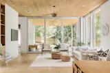 Scandinavian living room with floor to ceiling aluminum sliding doors from VALO Windows and Doors. Thermotreated wood cladding continues from inside ceiling to the outdoor living space creating continuity between the indoor and outdoor spaces