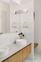 Japandi inspired bathroom featuring minimalist white oak floating vanities with white tiles and wood and leather towel hangers