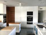 Kitchen, Microwave, Cooktops, Range, Refrigerator, Glass Tile Backsplashe, Range Hood, Undermount Sink, Pendant Lighting, White Cabinet, Wall Oven, Ceiling Lighting, Dishwasher, Quartzite Counter, and Limestone Floor Kitchen trolley to serve dining area.  Photo 7 of 16 in ASHAR by Amit Upadhye