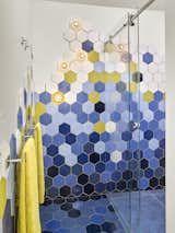 A colorful bathroom in graduating hues of blue with pops of chartreuse boasts locally made hexagonal tile. 