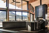 The warm industrial kitchen celebrates views of Rocky Mountain National Park beyond. A see-through, steel fireplace becomes a glowing beacon that warms the kitchen and living room at the heart of the home. 
