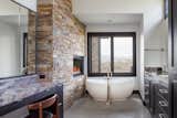 Nestled against the built-in fireplace, this modern, freestanding tub also catches the views from outside in this roomy bathroom.