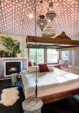 The bed was custom designed and installed in the center of the room, and the canopy is covered in Moroccan-style fabric. All of the trim, doors, and woodwork was imported from Morocco. Also from Morocco are the light fixtures, bone-inlay mirror, and octagonal side tables. The ceiling and wall border detail was hand-stenciled in paint.