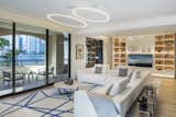 A bright and sleek living area faces the terrace, illuminated by a modern LED chandelier 