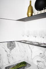 The home bar in the condo's kitchen features Carrara marble with metal shelving for a modern look. 